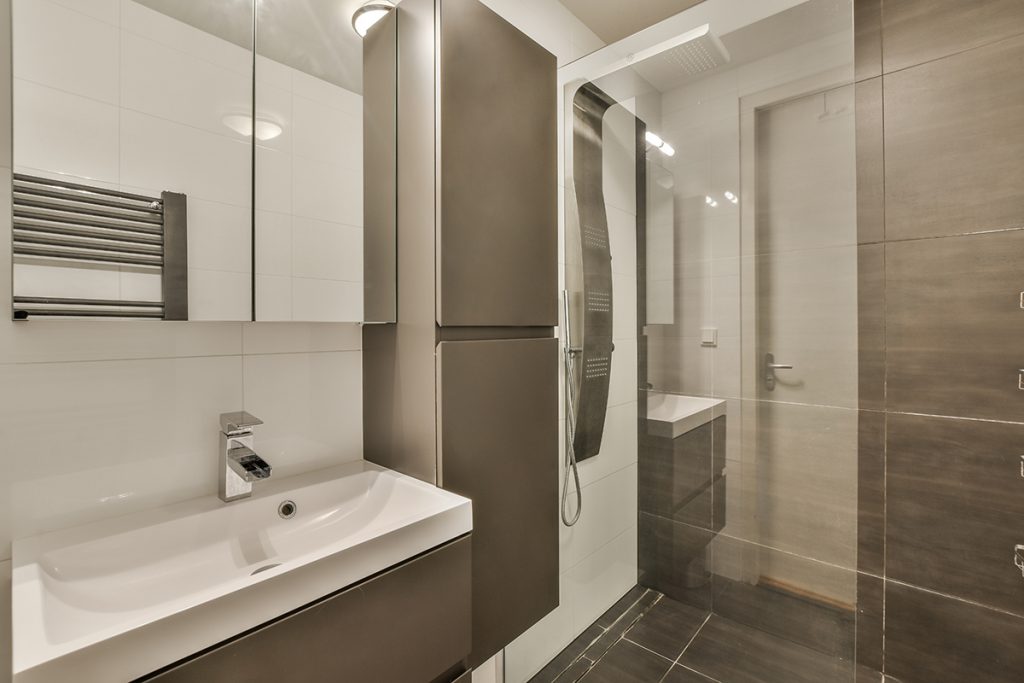 a modern bathroom with white and gray tiles on the walls, along with a large mirror in the shower stall
